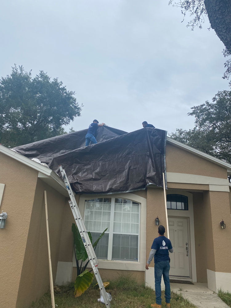 Men covering the roof of the house with foil